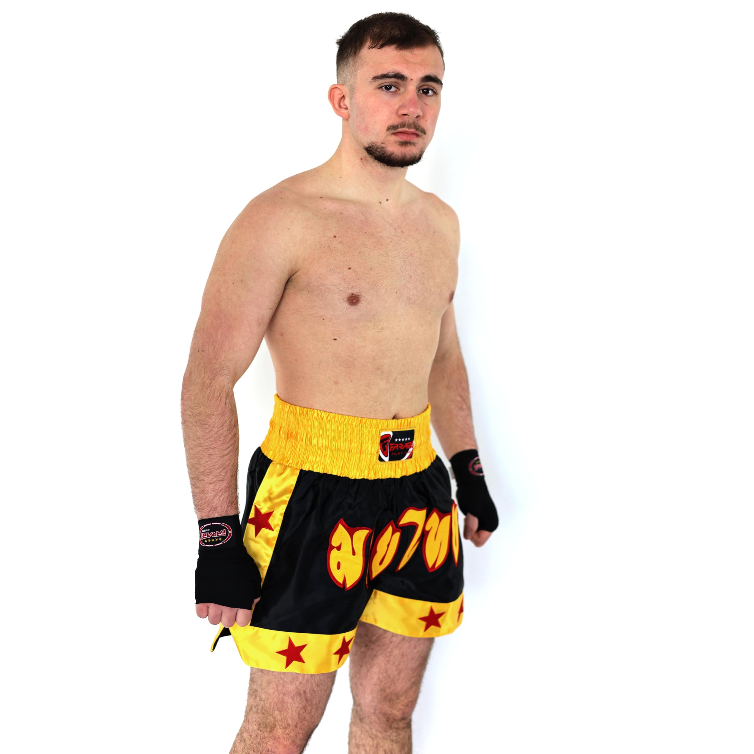 Farabi Sports Muay Thai fighter wearing black and yellow shorts with fiery lettering, showcasing readiness for combat.